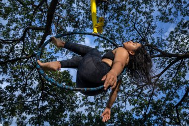Young Latin American woman in the open-air aerial hoop