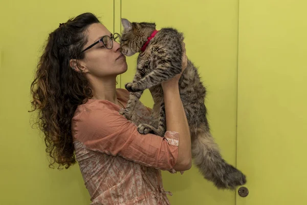 Latin American woman holds in her arms and plays affectionately with her cat