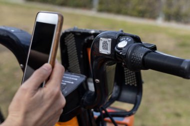 Cep telefonunda bisiklet kiralama uygulaması kullanan kişi