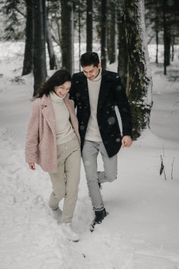 Genç bir çift kış ormanlarında dar bir patika boyunca yürür. Yüksek kalite fotoğraf