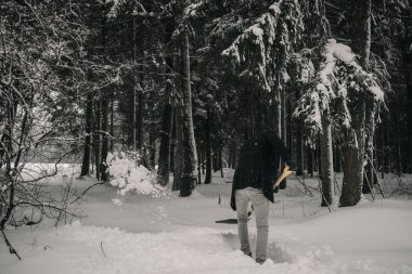 Bir adam kış ormanında kar temizler.