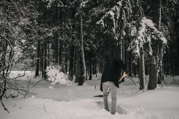 Bir adam kış ormanında kar temizler.