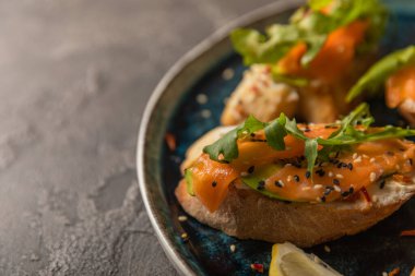 Büyük mavi bir tabakta somon avokadosu ve roka ile nefis bir bruschetta. Boşluğu kopyala