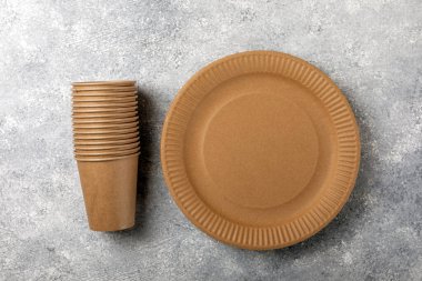 Çevre dostu tek kullanımlık kağıt sofra takımı. Kağıt bardak, beton arka planda kağıt tabak. Geri dönüşüm veya yeşil kavram.