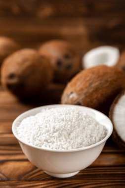 Kâsede hindistan cevizi gevreği, ahşap arka planda hindistan cevizi. Yakın plan. Boşluğu kopyala.