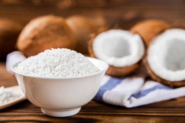 Kâsede hindistan cevizi gevreği, ahşap arka planda hindistan cevizi. Yakın plan. Boşluğu kopyala.