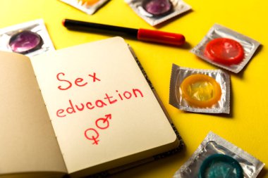 Prezervatif, keçeli kalem ve sarı arka planda 