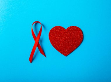 Mavi arka planda kırmızı kalpli kırmızı kurdele, HIV, AIDS ve kanserle mücadelenin sembolü. yoksul konsepte yardım