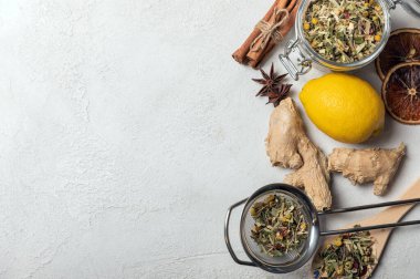 Yeşil çay yapraklı bitkisel çay şeffaf bir kavanozda, limon, tarçın, beyaz arka planda çay süzgeci. Çay konsepti. Yukarıdan bak. Boşluğu kopyala.