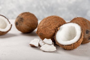 Hafif çimento arka planında yarım hindistan cevizi. Hindistan cevizi kremalı ve tereyağlı kompozisyon. Vejetaryen yemeği. Kopyalamak için boşluk.