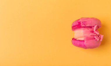 Yumuşak sarı-turuncu kağıt arka planda lezzetli çilekli kurabiyeler. Fransız badem kurabiyesi. Mutfak yemeği konsepti. Uzayı kopyala Yukarıdan görünüm.