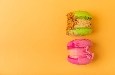 Yumuşak sarı-turuncu kağıt arka planda lezzetli çilekli kurabiyeler. Fransız badem kurabiyesi. Mutfak yemeği konsepti. Uzayı kopyala Yukarıdan görünüm.