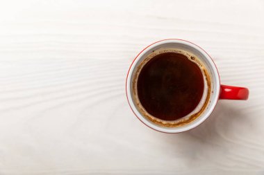 Beyaz desenli bir ahşap üzerinde bir fincan mis kokulu sıcak kahve. Sıcak sıcak içecek. İyi sabahlar. Sabah konsepti. Yukarıdan bak. Kopyalanacak yer.