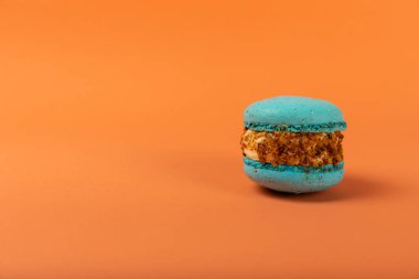 Turuncu arka planda Fransız kurabiyeleri. Mavi ve armutlu makarnalar. Fransız tatlısı. Güzel masa. Boşluğu kopyala. Mesaj için yer.