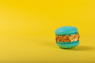 Sarı arka planda Fransız kurabiyeleri. Mavi ve armutlu makarnalar. Fransız tatlısı. Güzel masa. Boşluğu kopyala. Mesaj için yer.