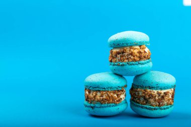 Mavi arka planda Fransız kurabiyeleri. Mavi ve armutlu makarnalar. Fransız tatlısı. Güzel masa. Boşluğu kopyala. Mesaj için yer.