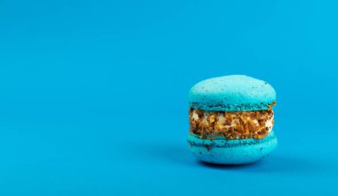 Mavi arka planda Fransız kurabiyeleri. Mavi ve armutlu makarnalar. Fransız tatlısı. Güzel masa. Boşluğu kopyala. Mesaj için yer.