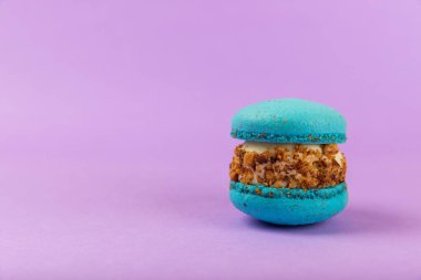 Leylak arkaplanlı Fransız kurabiyeleri. Mavi ve armutlu makarnalar. Fransız tatlısı. Güzel masa. Boşluğu kopyala. Mesaj için yer.