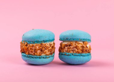 Pembe arka planda Fransız kurabiyeleri. Mavi ve armutlu makarnalar. Fransız tatlısı. Güzel masa. Boşluğu kopyala. Mesaj için yer.