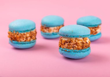 Pembe arka planda Fransız kurabiyeleri. Mavi ve armutlu makarnalar. Fransız tatlısı. Güzel masa. Boşluğu kopyala. Mesaj için yer.