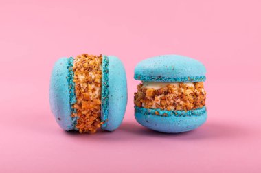 Pembe arka planda Fransız kurabiyeleri. Mavi ve armutlu makarnalar. Fransız tatlısı. Güzel masa. Boşluğu kopyala. Mesaj için yer.