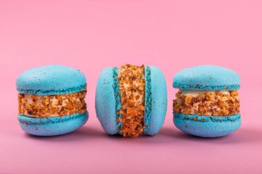 Pembe arka planda Fransız kurabiyeleri. Mavi ve armutlu makarnalar. Fransız tatlısı. Güzel masa. Boşluğu kopyala. Mesaj için yer.