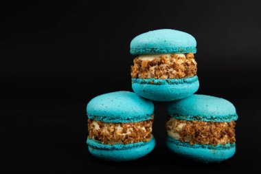 Siyah arka planda Fransız kurabiyeleri. Mavi ve armutlu makarnalar. Fransız tatlısı. Güzel masa. Uzayı kopyala Metin için yer.