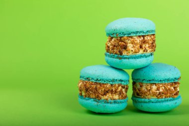 Yeşil arka planda Fransız makarnası. Mavi ve armutlu makarnalar. Fransız tatlısı. Güzel masa. Uzayı kopyala Metin için yer.