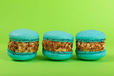 Yeşil arka planda Fransız makarnası. Mavi ve armutlu makarnalar. Fransız tatlısı. Güzel masa. Uzayı kopyala Metin için yer.