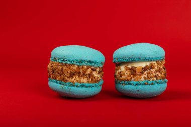 Kırmızı arka planda Fransız makarnası. Mavi ve armutlu makarnalar. Fransız tatlısı. Güzel masa. Uzayı kopyala Metin için yer.