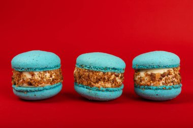 Kırmızı arka planda Fransız makarnası. Mavi ve armutlu makarnalar. Fransız tatlısı. Güzel masa. Uzayı kopyala Metin için yer.