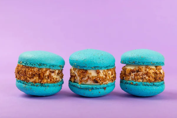 Leylak arkaplanlı Fransız kurabiyeleri. Mavi ve armutlu makarnalar. Fransız tatlısı. Güzel masa. Boşluğu kopyala. Mesaj için yer.