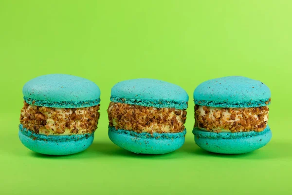 Yeşil arka planda Fransız makarnası. Mavi ve armutlu makarnalar. Fransız tatlısı. Güzel masa. Uzayı kopyala Metin için yer.