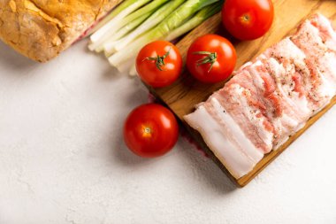 Domuz yağı, yeşil soğan, ev yapımı ekmek ve kiraz domatesli gri taşlı arka plan. Salo olsun. Lezzetli tuzlu domuz yağı ve biber. Kopya için yer var. Metin için boşluk.