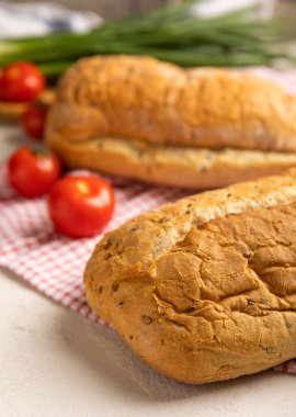 Taze ev yapımı ekmek, yeşil soğanlı ve gri çimento arka planda mutfak havlusunda kiraz domatesli. Keten tohumlu ekmek, ayçiçeği tohumu ve ekşi ekmek. Organik ev yapımı hamur işleri.. 