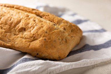 Gri çimento arka planda mutfak havlusunda taze ev yapımı ekmek. Keten tohumlu ekmek, ayçiçeği tohumu ve ekşi ekmek. Organik ev yapımı hamur işleri. Kopyalanacak yer.