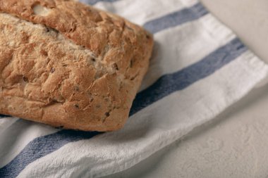 Gri çimento arka planda mutfak havlusunda taze ev yapımı ekmek. Keten tohumlu ekmek, ayçiçeği tohumu ve ekşi ekmek. Organik ev yapımı hamur işleri. Kopyalanacak yer.