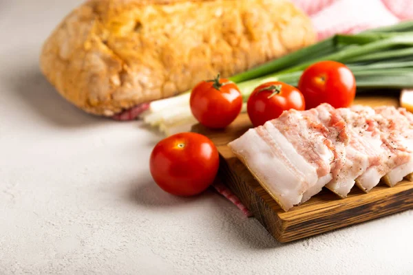 Domuz yağı, yeşil soğan, ev yapımı ekmek ve kiraz domatesli gri taşlı arka plan. Salo olsun. Lezzetli tuzlu domuz yağı ve biber. Kopya için yer var. Metin için boşluk.