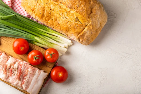 Domuz yağı, yeşil soğan, ev yapımı ekmek ve kiraz domatesli gri taşlı arka plan. Salo olsun. Lezzetli tuzlu domuz yağı ve biber. Kopya için yer var. Metin için boşluk.