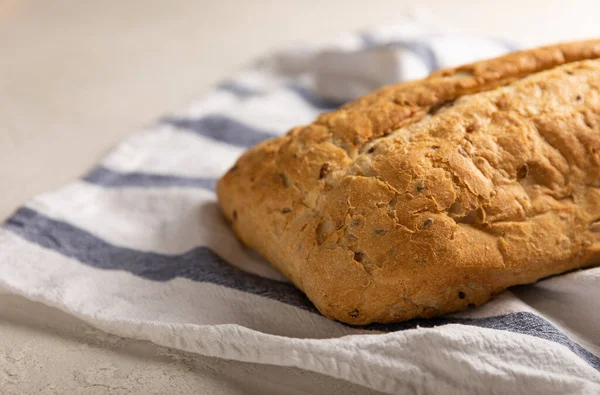 Gri çimento arka planda mutfak havlusunda taze ev yapımı ekmek. Keten tohumlu ekmek, ayçiçeği tohumu ve ekşi ekmek. Organik ev yapımı hamur işleri. Kopyalanacak yer.