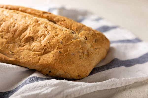 Gri çimento arka planda mutfak havlusunda taze ev yapımı ekmek. Keten tohumlu ekmek, ayçiçeği tohumu ve ekşi ekmek. Organik ev yapımı hamur işleri. Kopyalanacak yer.