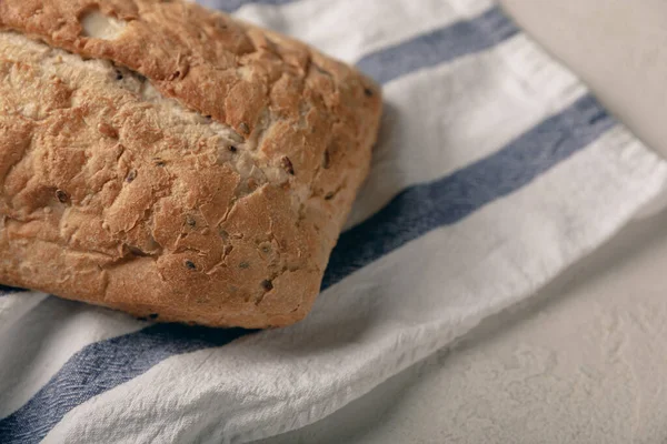 Gri çimento arka planda mutfak havlusunda taze ev yapımı ekmek. Keten tohumlu ekmek, ayçiçeği tohumu ve ekşi ekmek. Organik ev yapımı hamur işleri. Kopyalanacak yer.