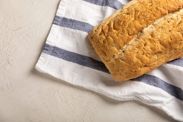 Gri çimento arka planda mutfak havlusunda taze ev yapımı ekmek. Keten tohumlu ekmek, ayçiçeği tohumu ve ekşi ekmek. Organik ev yapımı hamur işleri. Kopyalanacak yer.