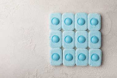 Gri desenli arka planda su yumuşatma hapları. Kireç boyutunu engelleyen çamaşır makineleri ve bulaşık makineleri için kapsüller. Kopyalanacak yer.