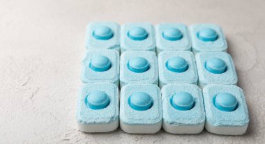 Gri desenli arka planda su yumuşatma hapları. Kireç boyutunu engelleyen çamaşır makineleri ve bulaşık makineleri için kapsüller. Kopyalanacak yer.