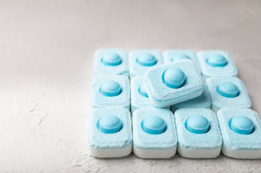 Gri desenli arka planda su yumuşatma hapları. Kireç boyutunu engelleyen çamaşır makineleri ve bulaşık makineleri için kapsüller. Kopyalanacak yer.