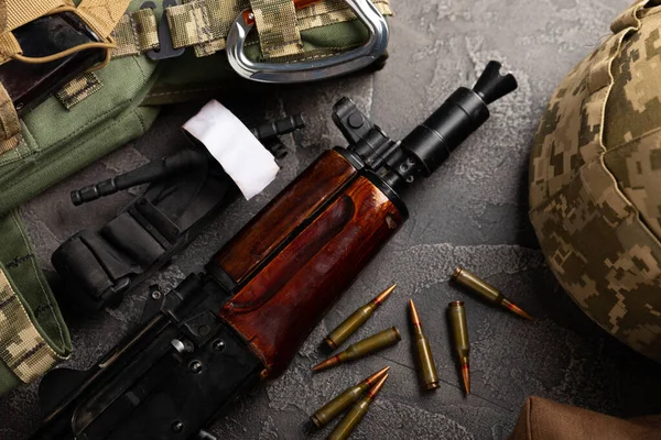Askeri zırh, miğfer ve mühimmat, bir Kalaşnikof müfrezeli saldırı tüfeği ve ilk yardım turnikesi. Siyah bir mermer masanın üzerinde. Ordu kurşun geçirmez yelek. Düz yatıyordu. Askeri kavram.