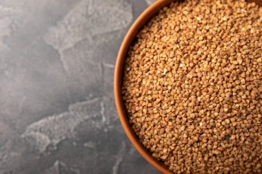 Siyah mermer arka planda bir kasede karabuğday. Çiğ karabuğday. Glütensiz güveç için malzemeler. Sağlıklı yiyecekler. Kopyalanacak yer.