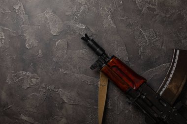 Siyah desenli mermer üzerine Kolashnikov saldırı tüfeği içeren mermiler ve cephane şarjörü. Metinde yer alan kompozisyon. Tahta arka planda tüfek ve kartuş. Askeri kavram.