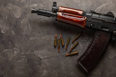 Siyah desenli mermer üzerine Kolashnikov saldırı tüfeği içeren mermiler ve cephane şarjörü. Metinde yer alan kompozisyon. Tahta arka planda tüfek ve kartuş. Askeri kavram.